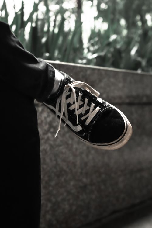 Free Fashionable black sports shoe with laces resting on a stone ledge outdoors. Stock Photo