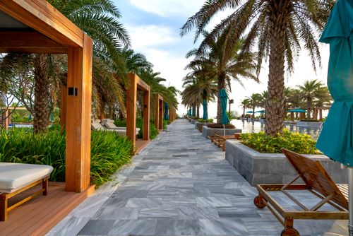 Free Stunning resort walkway lined with palm trees and relaxation spots by a poolside. Stock Photo