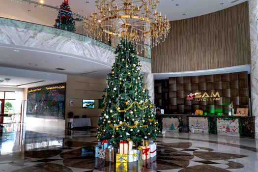 Luxurious hotel lobby featuring a grand Christmas tree adorned with ornaments and gifts.
