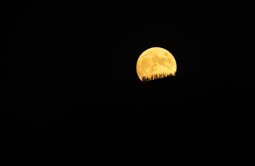 Free Full moon rising over hill silhouette at night in Redlands, CA, USA. Stock Photo
