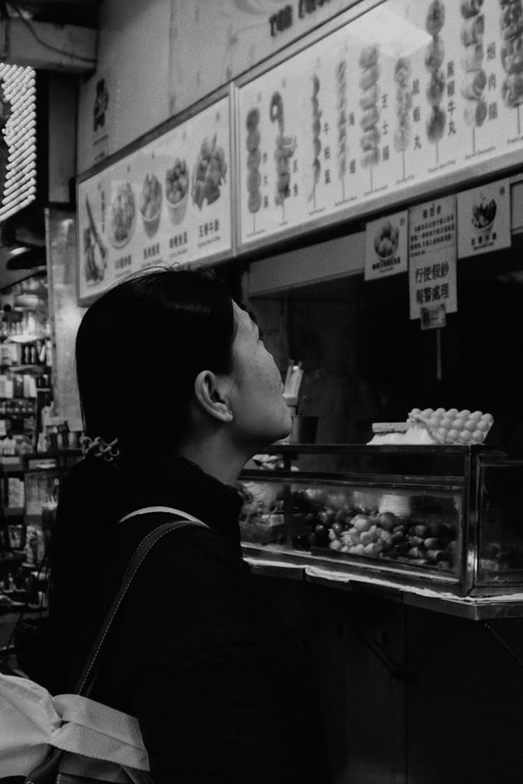 Black And White Photo Of A Woman Looking At Menu