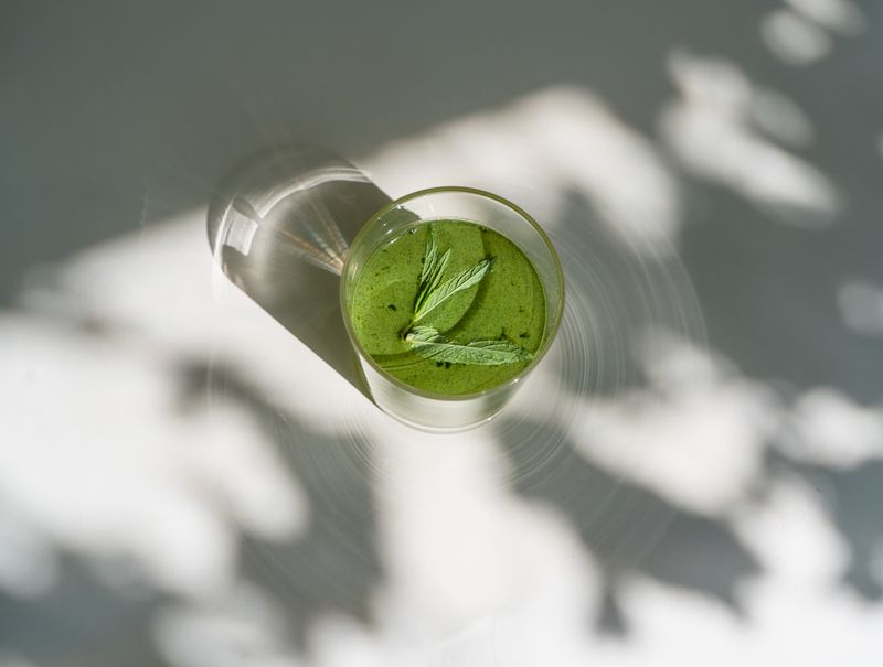 An iced green matcha drink with mint, seen from above in dappled shade