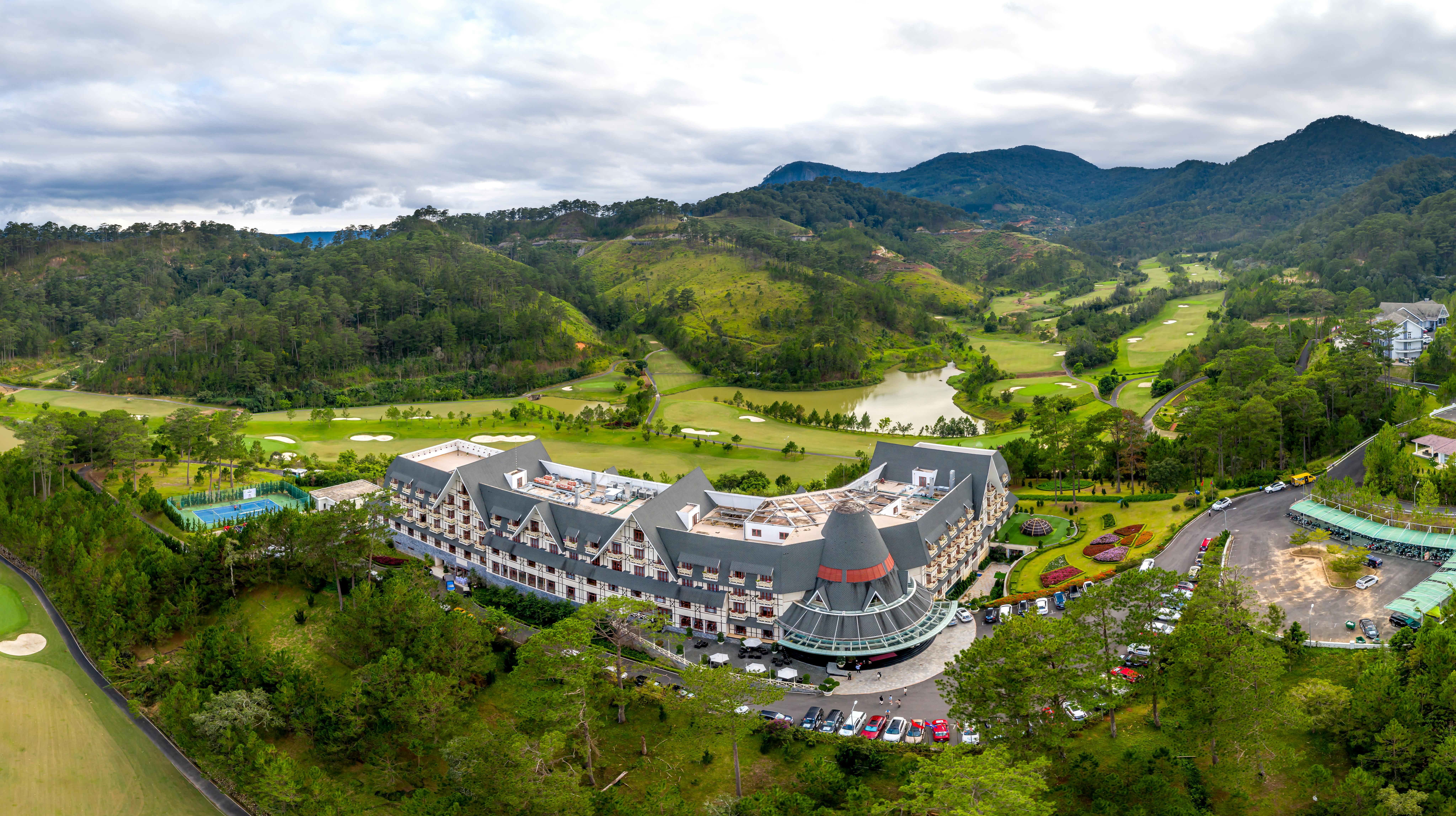 Scenic aerial view of a luxurious mountain resort surrounded by lush greenery and a golf course.