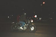 夜晚，一个人骑着摩托车，行驶在路灯照亮的城市街道上