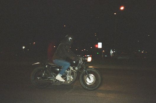 夜晚，一个人骑着摩托车，行驶在路灯照亮的城市街道上