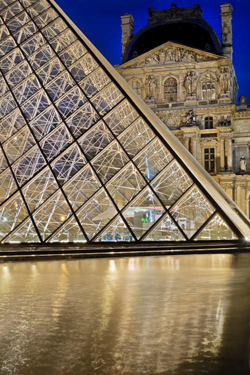 Free I.M. Pei’s pyramid, the main entrance to the Louvre Museum with pavillon Denon in the background at night. Stock Photo