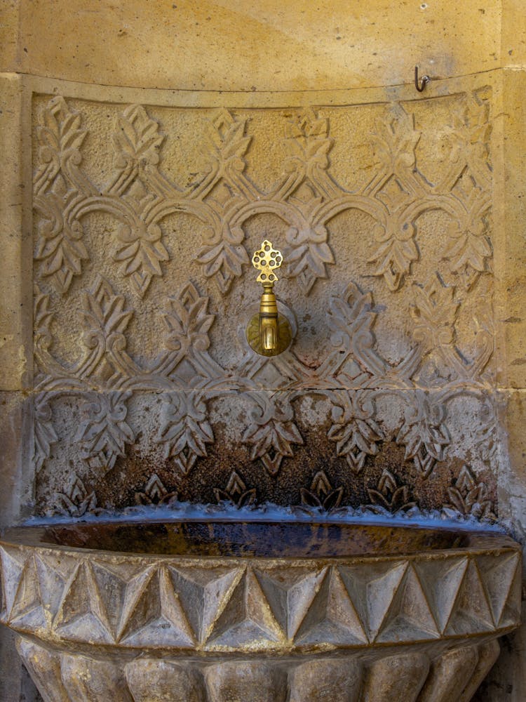 A Gold Faucet On Brown Concrete Wall