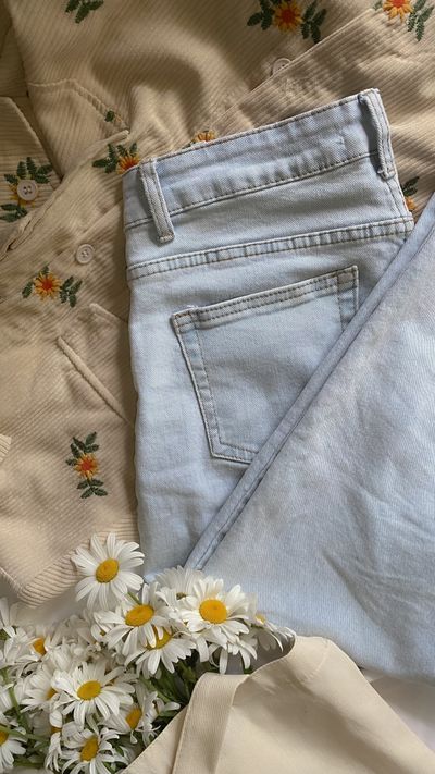 Light-wash denim jeans folded on a bed — photo by Karina Kholina on Pexels