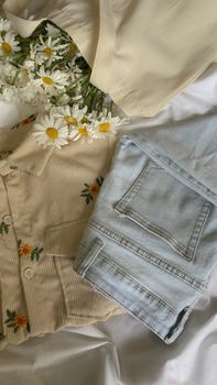 Flat lay of a casual outfit featuring floral embroidery and daisies on white fabric, captured with an iPhone.