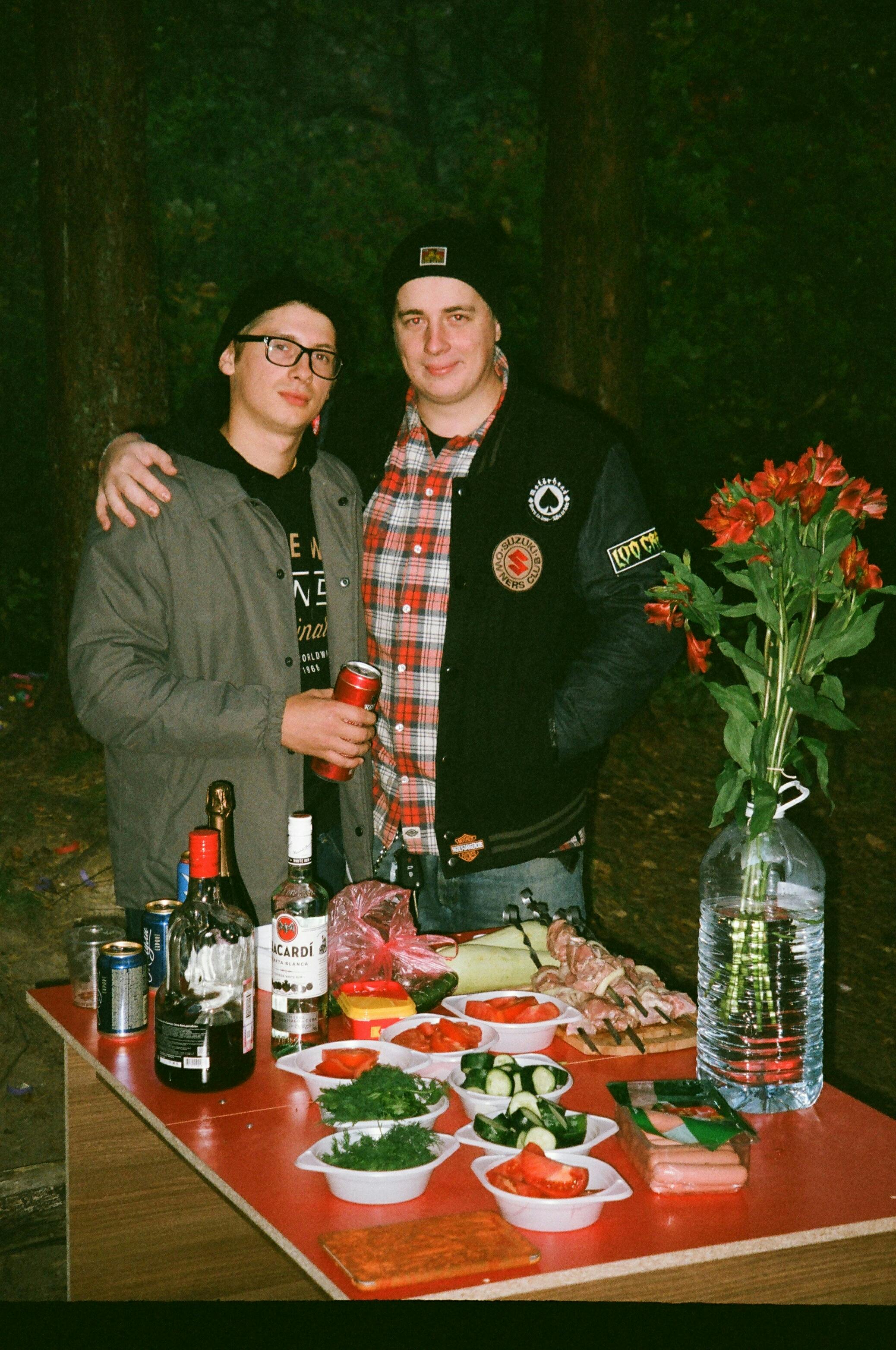 two men standing beside each other at the back of table