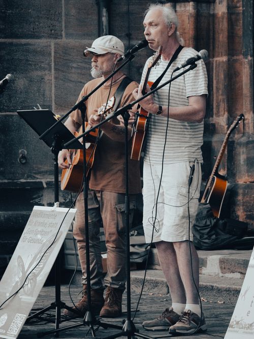 Free Two elderly men perform with guitars on the street, showcasing live music and talent. Stock Photo