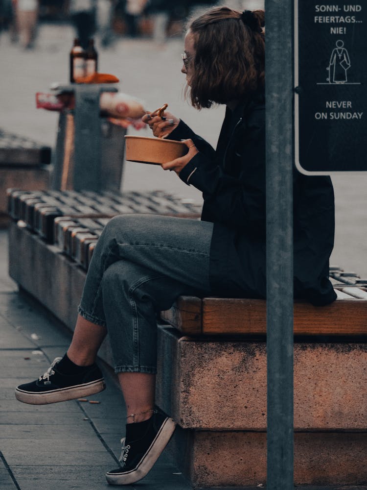 Woman Sitting On A Bench Eating