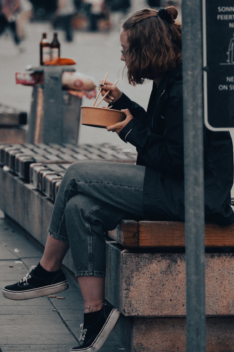 Woman Sitting On Concrete Bench While Eating