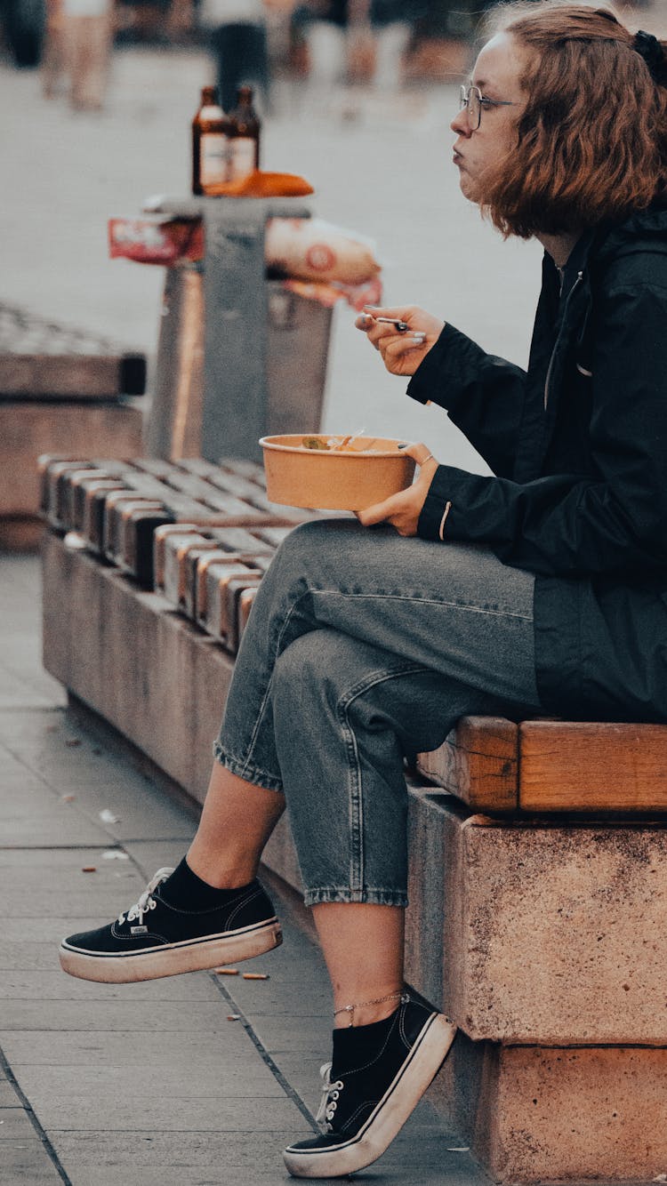 Woman Sitting On Concrete Bench While Eating