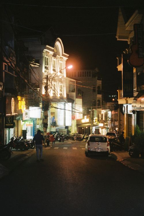 Free A bustling street at night with illuminated buildings and parked vehicles in a lively urban area. Stock Photo