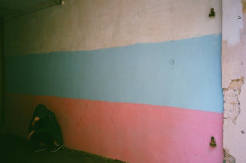 倚在蓝色，白色和粉红色的墙上的人