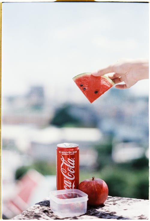 Close-up of Holding a Sliced of Watermelon Above Soda Can