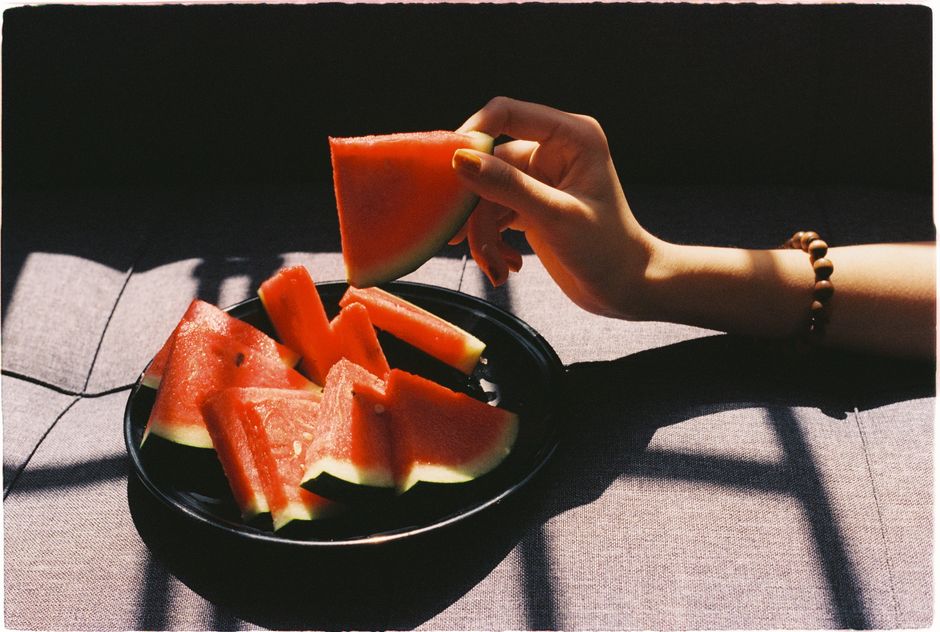 A hand picking a slice of watermelon in natural light.