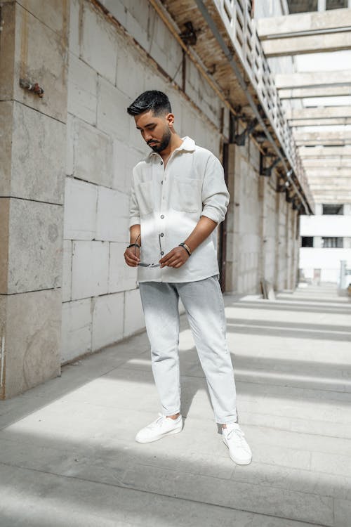 Free Man in White Dress Shirt and Gray Pants Standing on White Concrete Floor Stock Photo