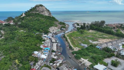 Free Beautiful aerial shot of a coastal village beside the ocean with lush hills and fishing boats. Stock Photo
