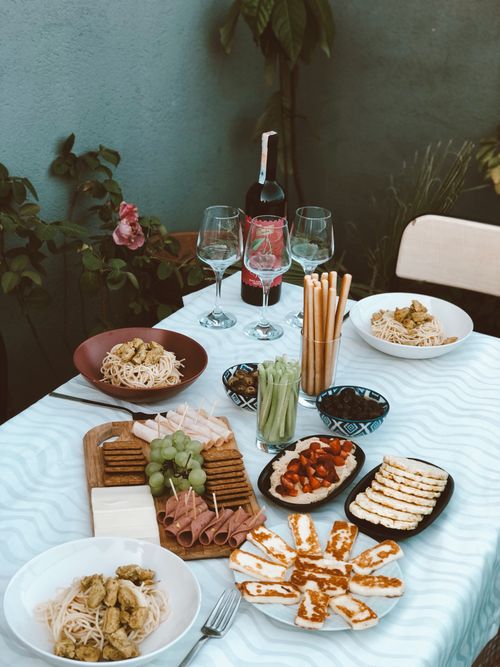 Free A beautifully set table outdoors with wine, cheese, pasta, and snacks for a delightful lunch. Stock Photo