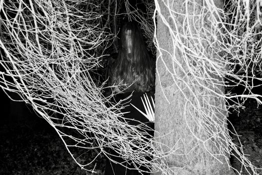 An eerie figure stands ominously among bare trees at night, creating a spooky Halloween atmosphere.