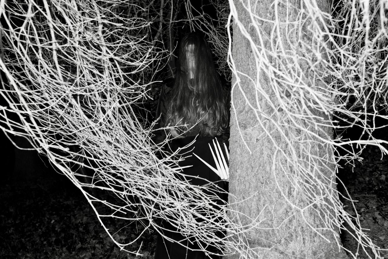 an eerie figure stands ominously among bare trees at night creating a