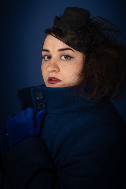 Free Stylish portrait of a woman in a blue coat and hat, set against a dark background. Stock Photo