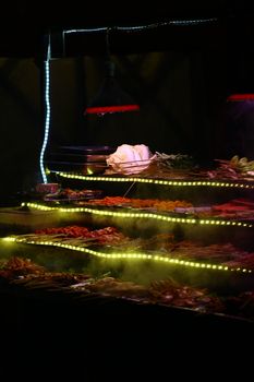 A colorful and vibrant street food stall at night showcasing a variety of skewers and vegetables.