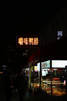 Street food vendors at a lively night market featuring illuminated signage and bustling ambiance.