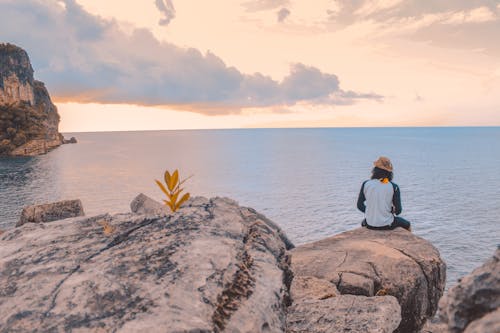 Free Person Sitting on Cliff Near Body of Water Stock Photo
