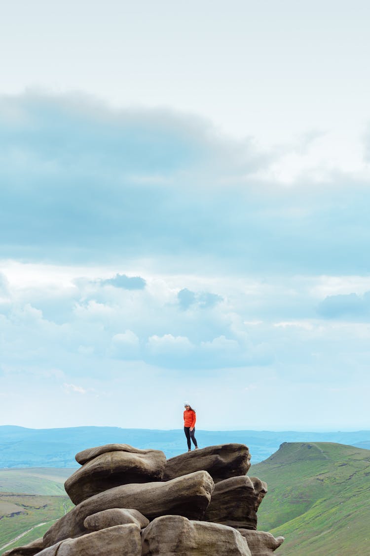 Person Standing On Granite Rocks Under White Clouds