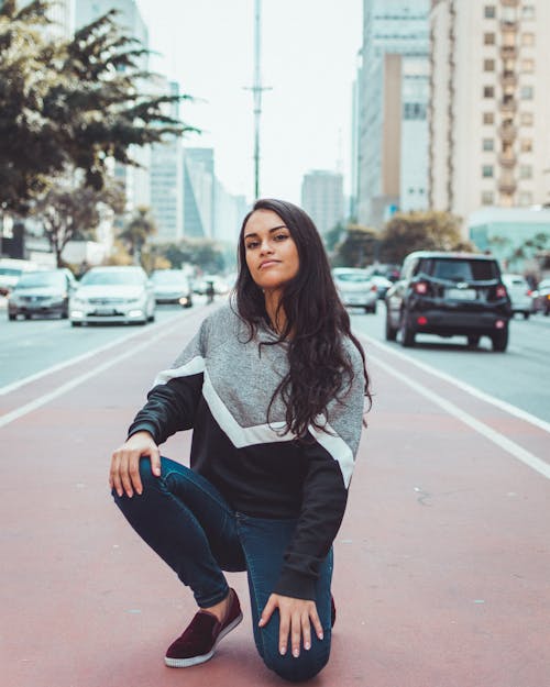 Woman Kneeling on Street Near Building