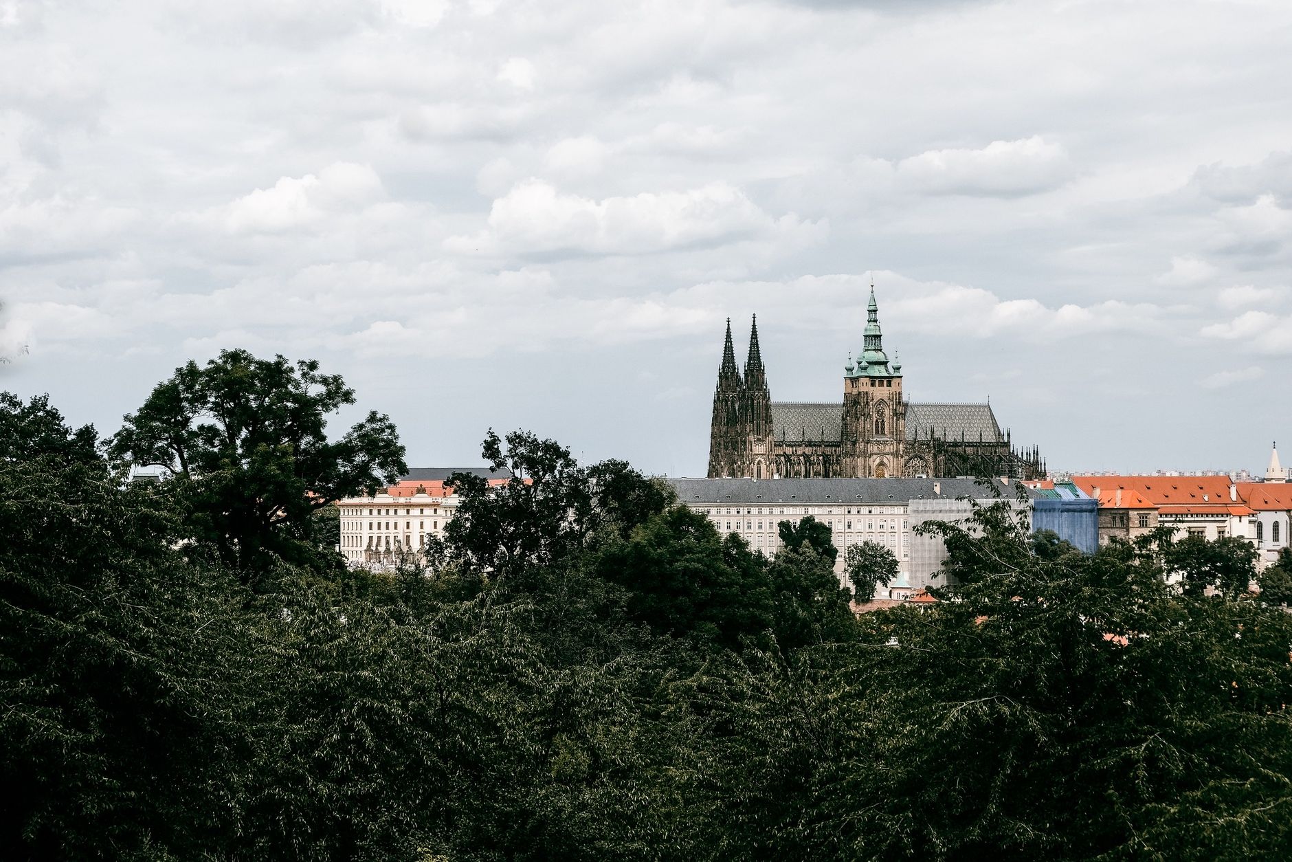 A picturesque view of Prague Castle with lush greenery and cloudy sky, capturing the essence of historical architecture.