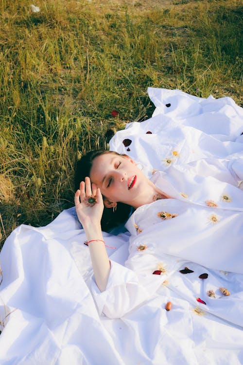 Elegant Woman in White Dress Lying on Green Grass