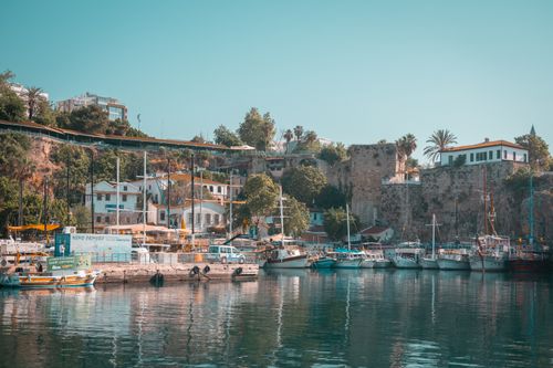 Free Beautiful harbor with docked boats, hillside buildings, and lush greenery under a clear sky. Stock Photo