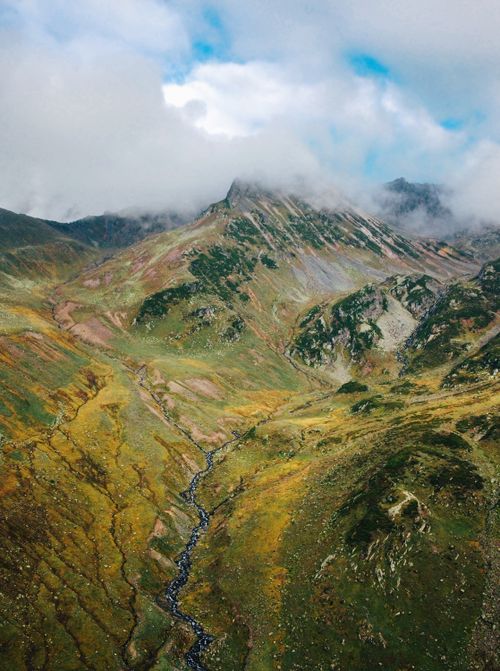 Free A breathtaking view of rugged mountains partly covered by clouds, offering a serene and majestic landscape. Stock Photo