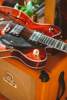 Red electric guitar resting on an amplifier in a cozy indoor setting.
