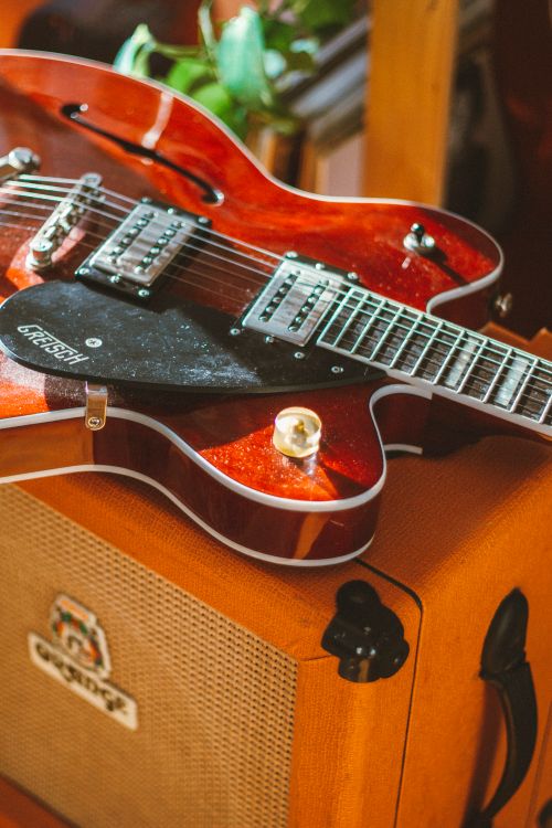 Free Red electric guitar resting on an amplifier in a cozy indoor setting. Stock Photo