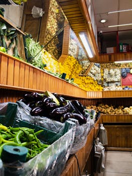 Indoor market stall displaying fresh vegetables including peppers, eggplants, and potatoes.