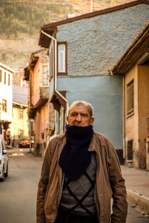 Free An elderly man with a scarf walks down a colorful street in Afyonkarahisar, Türkiye. Stock Photo