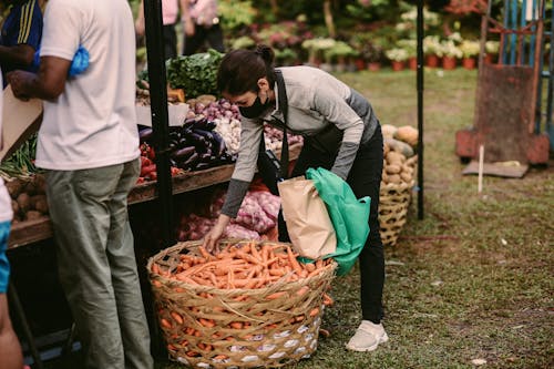 Female Vendor picking Carrots from a Wicker Basket 