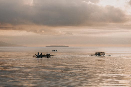 Tranquil scene of traditional outrigger boats on calm sea under moody sunset skies.