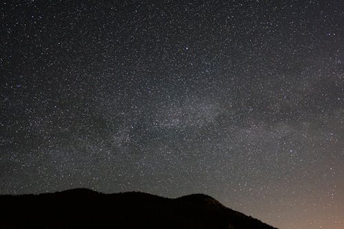 Free Stars Glowing in Night Sky Over Mountains Stock Photo
