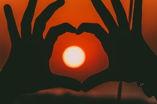 Free Silhouetted hands create a heart shape against a vivid sunset in Aaqrabâte, Syria. Stock Photo