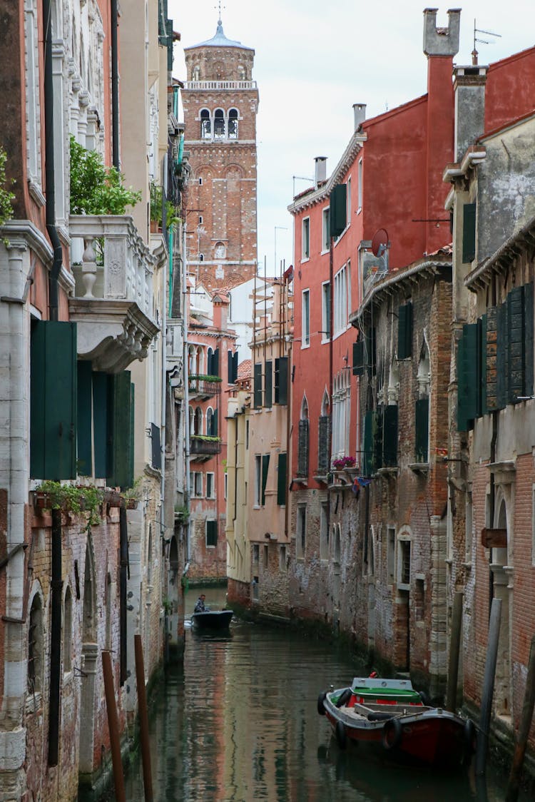 Gondolas Floating On A Canal Between Concrete Houses