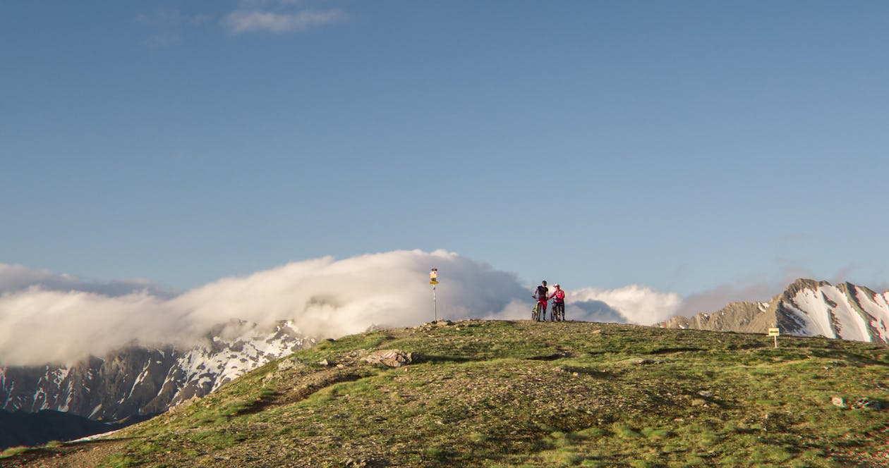 免费 两个男人站在白雪覆盖的山附近的山上 素材图片