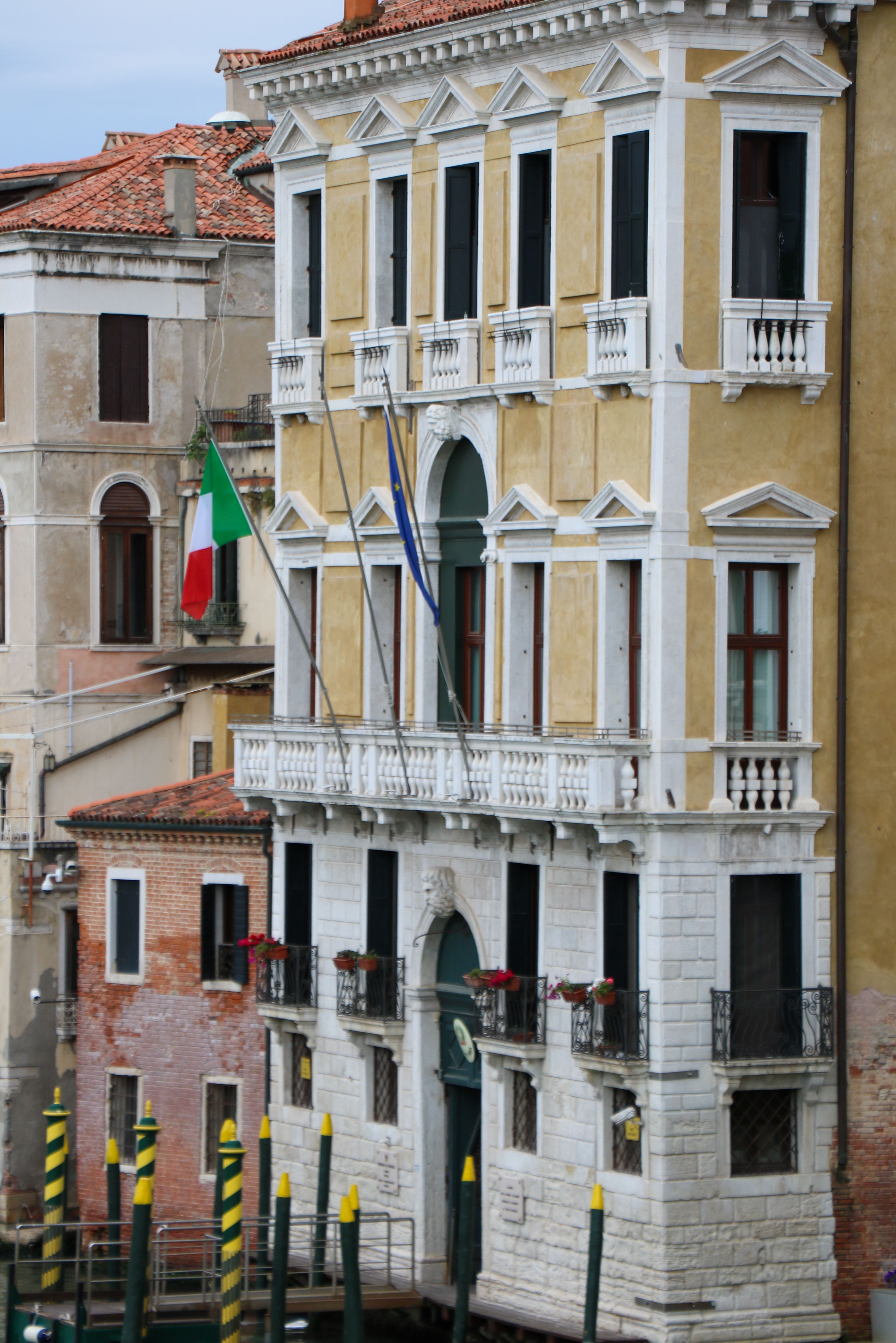 Elegant Venetian building with flags on a canal, showcasing classic architecture.