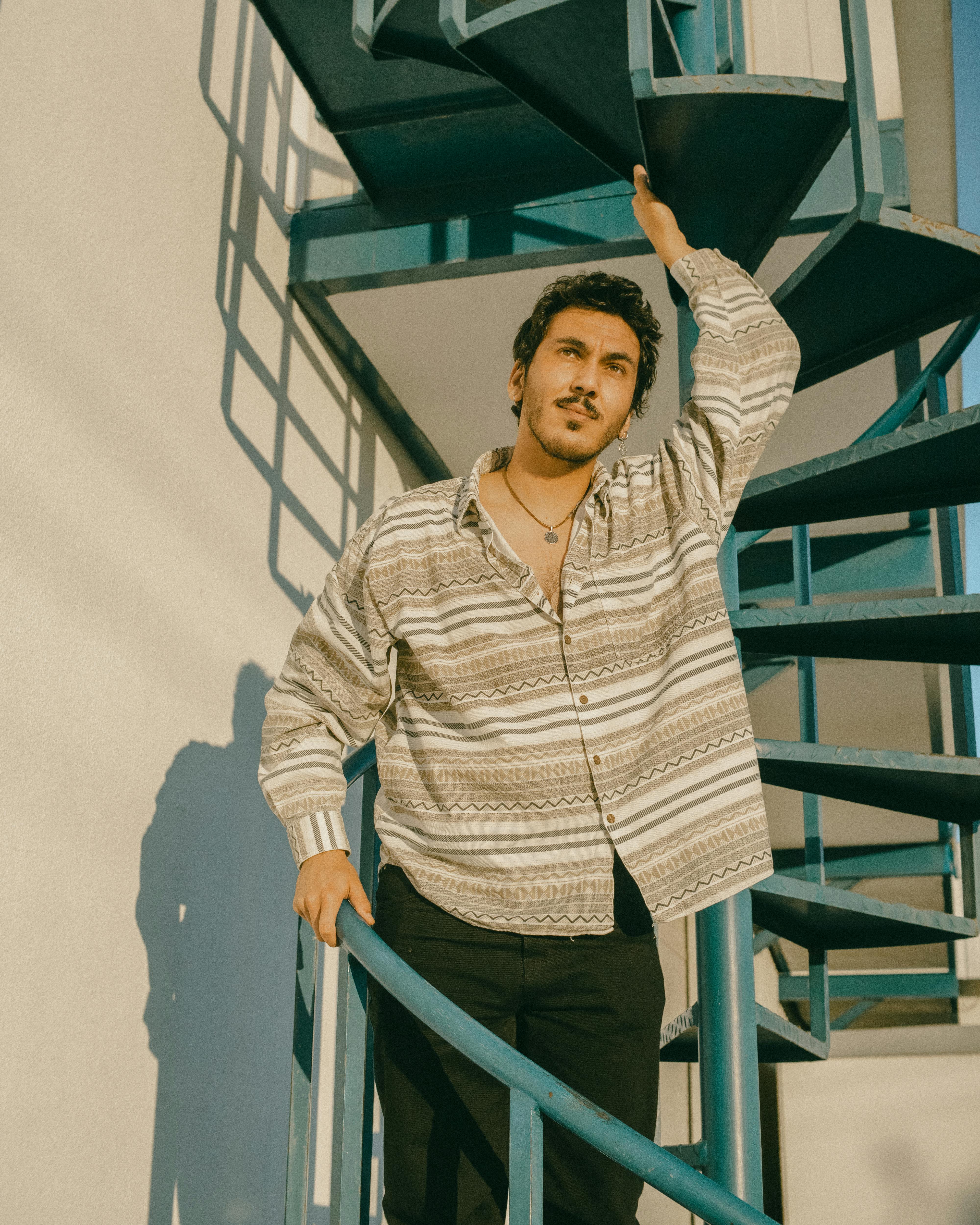 A fashionable man posing on a spiral staircase, capturing a modern and elegant look.
