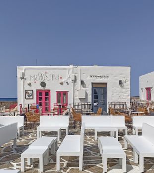 Sunny outdoor seating area at a Greek café with blue sky and vibrant accents.